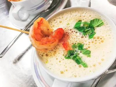 a bowl of soup with shrimp and greens on top at Pension Maria in Antermoia