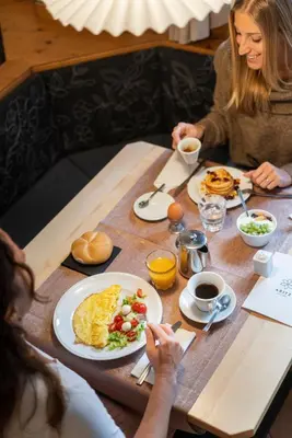 a group of people sitting at a table eating breakfast at Garni Aritz in Campitello di Fassa