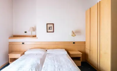 a bed in a room with two lamps on the wall at Garni Aritz in Campitello di Fassa