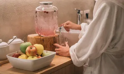 a woman standing in a kitchen mixer with a bowl of fruit at Garni Aritz in Campitello di Fassa