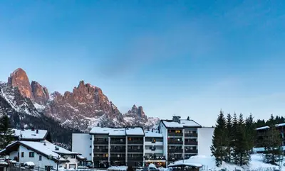 a hotel with snow covered mountains in the background at Residence Lastei in San Martino di Castrozza