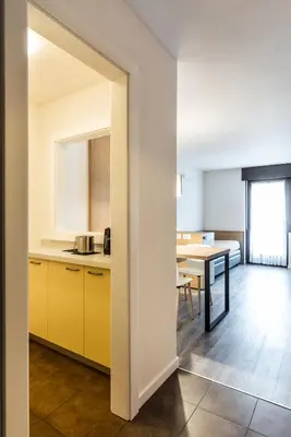 a kitchen and dining room with yellow cabinets and a table at Residence Lastei in San Martino di Castrozza