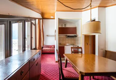 a kitchen and living room with a wooden table in a room at Residence Lastei in San Martino di Castrozza