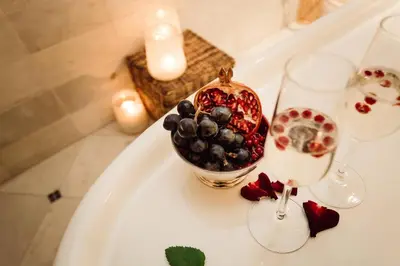 a bowl of fruit on a white table with glasses at Hotel Castel Rundegg (Adults Only) in Merano