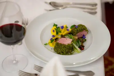 a plate of food on a table with a glass of wine at Hotel Castel Rundegg (Adults Only) in Merano