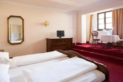 a hotel room with a bed and a mirror and a table at Hotel Castel Rundegg (Adults Only) in Merano