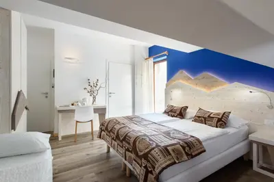 a bedroom with a bed and a table and a tv at Hotel Garni Roberta in Malga Ciapela