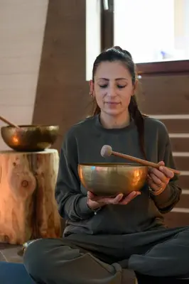 a woman sitting on the floor holding a bowl with chopsticks at Hotel Garni Roberta in Malga Ciapela