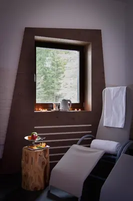 a room with a chair and a table and a window at Hotel Garni Roberta in Malga Ciapela