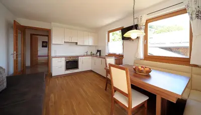 a kitchen with a wooden table and a dining room at Rumpelehof in Villandro