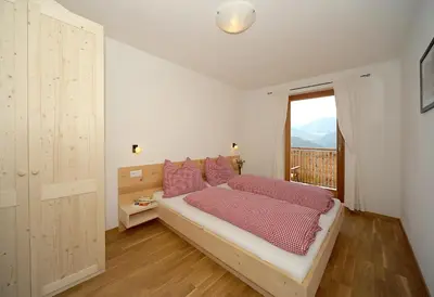 a bedroom with a bed with pink pillows and a window at Rumpelehof in Villandro