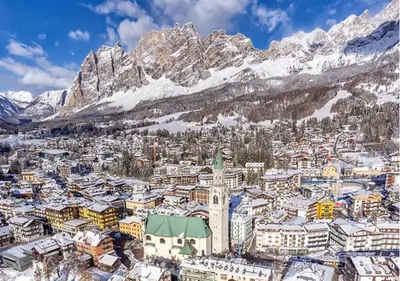 a city covered in snow with mountains in the background at Parc Hotel Victoria in Cortina dʼAmpezzo