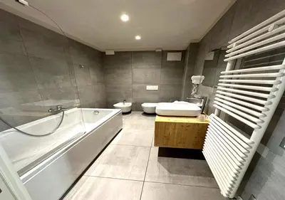 a bathroom with a tub and a toilet and a sink at Parc Hotel Victoria in Cortina dʼAmpezzo