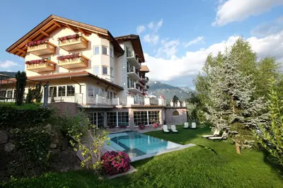 a building with a swimming pool in a yard at Hotel Lagorai Resort & Spa in Cavalese