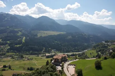 a house in the middle of a valley with mountains at Hotel Lagorai Resort & Spa in Cavalese