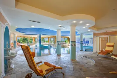 a living room with chairs and a pool at Hotel Lagorai Resort & Spa in Cavalese