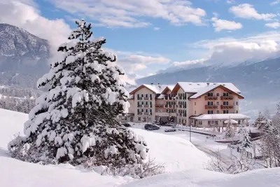 a snow covered christmas tree in front of a hotel at Hotel Lagorai Resort & Spa in Cavalese