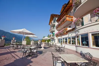 a patio with tables and chairs on a building at Hotel Lagorai Resort & Spa in Cavalese