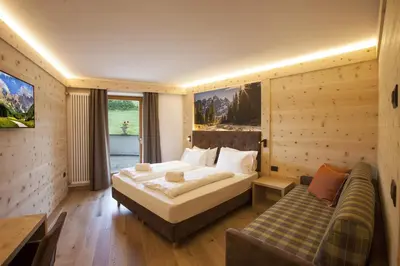 a bedroom with a large bed and a couch at Hotel Lagorai Resort & Spa in Cavalese