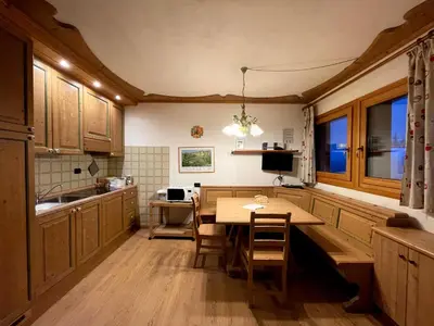 a kitchen with wooden cabinets and a table and chairs at Casa Cucciolo Falcade in Falcade