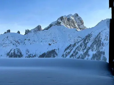 a snow covered mountain with a lake in front of it at Casa Cucciolo Falcade in Falcade