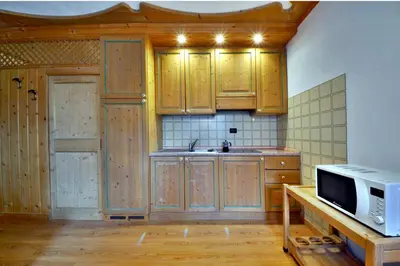 a kitchen with wooden cabinets and a microwave at Casa Cucciolo Falcade in Falcade