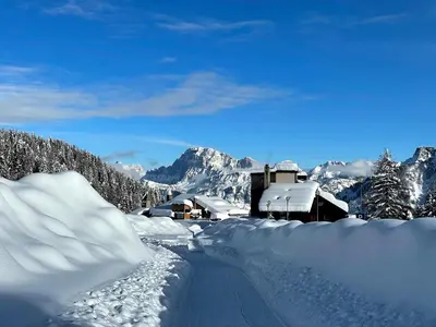 a road covered in snow with mountains in the background at Casa Cucciolo Falcade in Falcade