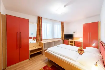 a bedroom with a bed with red cabinets and a television at Hotel Figl ***S in Bolzano