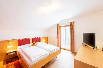 a bedroom with a large bed and a television at Hotel Figl ***S in Bolzano
