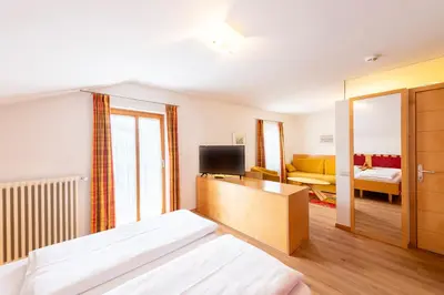 a bedroom with a bed and a television and a couch at Hotel Figl ***S in Bolzano