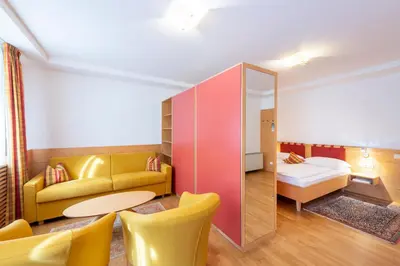 a room with a couch and a bed and a mirror at Hotel Figl ***S in Bolzano
