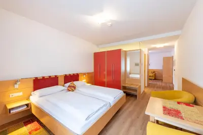 a bedroom with a large bed and a chair at Hotel Figl ***S in Bolzano