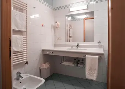 a white bathroom with a sink and a mirror at Hotel Figl ***S in Bolzano