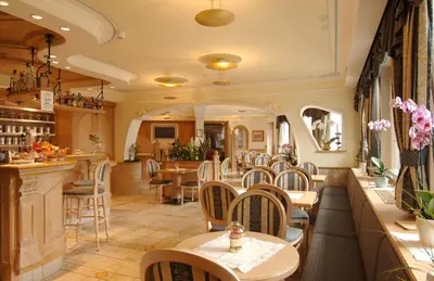 a restaurant with tables and chairs and a bar at Hotel Alle Alpi in Moena