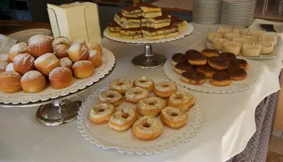 a table with several trays of donuts and other desserts at Hotel Alle Alpi in Moena