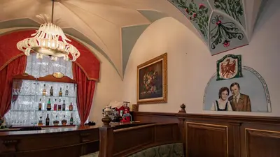 a bar in a room with a chandelier at Hotel Dolomiti Schloss in Canazei