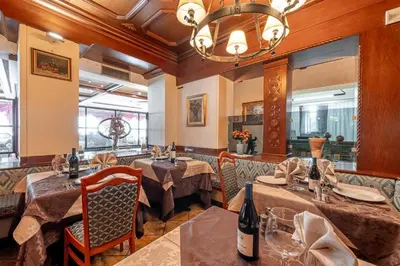 a restaurant with tables and chairs and a chandelier at Hotel Dolomiti Schloss in Canazei