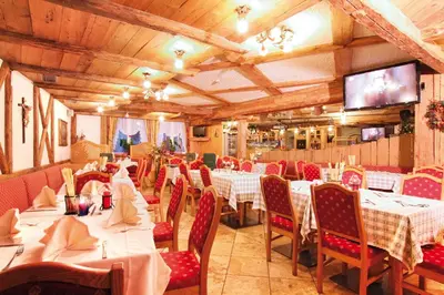 a restaurant with tables and chairs and a flat screen tv at Hotel Dolomiti Schloss in Canazei