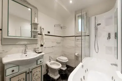 a white bathroom with a toilet and a sink at Hotel Dolomiti Schloss in Canazei