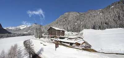 a ski lodge in the mountains with snow on the ground at Hotel il Caminetto Sport in Canazei