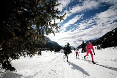 three people cross country skiing in the snow at Hotel il Caminetto Sport in Canazei