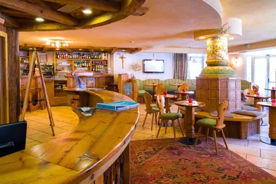 a restaurant with a bar and tables and chairs at Hotel Bellevue in Canazei