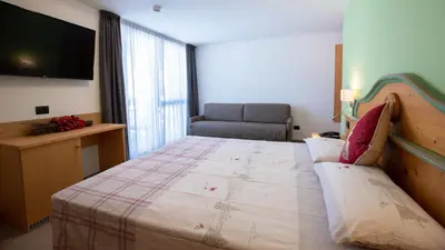 a bedroom with a large bed with a flat screen tv at Hotel Bellevue in Canazei