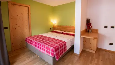 a bedroom with a bed with a red and white blanket at Hotel Bellevue in Canazei