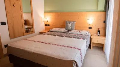 a small bedroom with a bed and a mirror at Hotel Bellevue in Canazei