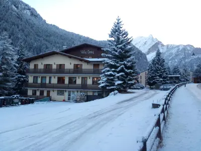 a snow covered road in front of a building at IHR Hotel Villa Emma in Canazei