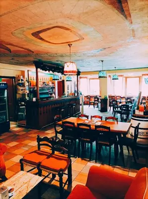 a restaurant with tables and chairs and a bar at IHR Hotel Villa Emma in Canazei