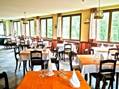 a restaurant with white tables and chairs and windows at IHR Hotel Villa Emma in Canazei