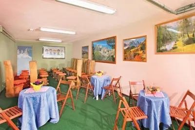 a room with tables and chairs and paintings on the walls at Hotel Villetta Maria Cottage in Canazei