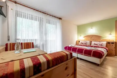 a bedroom with two beds and a window at Hotel Villetta Maria Cottage in Canazei